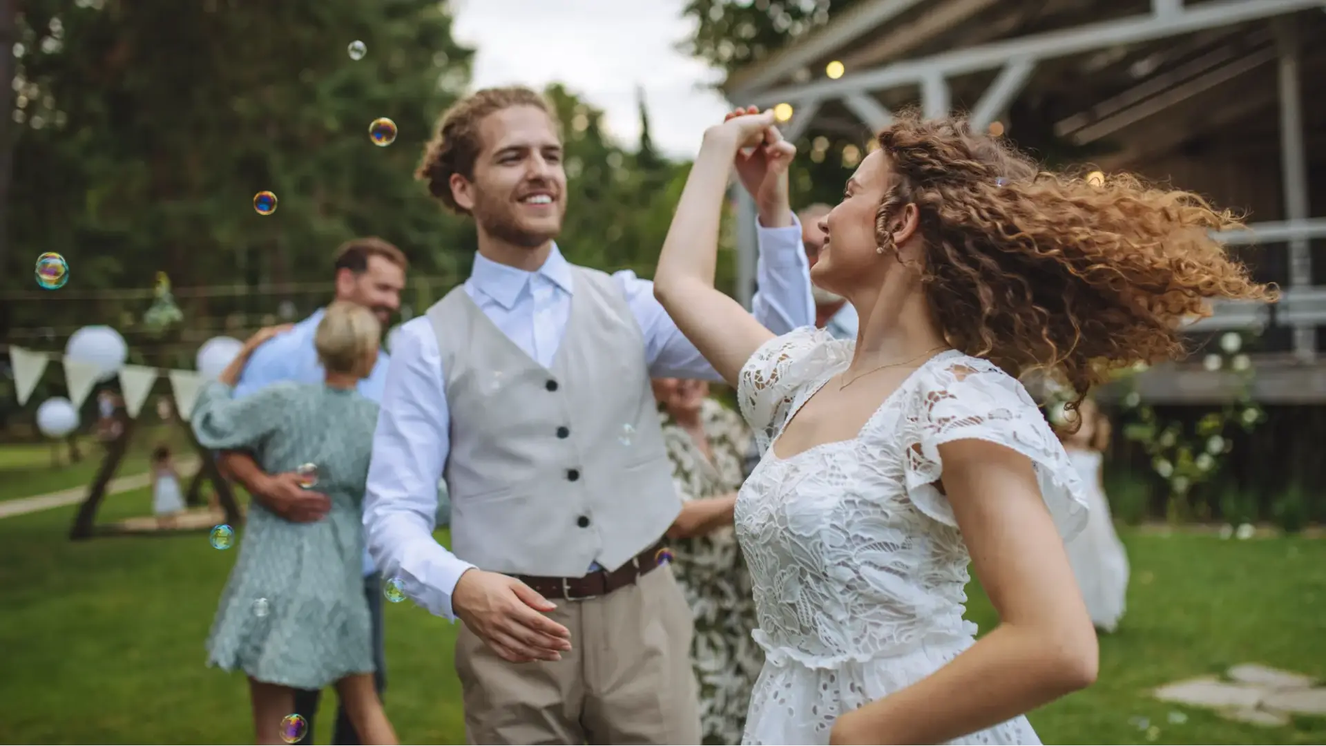 Bride and groom holding hands and dancing at small garden wedding. First wedding dance outdoors.